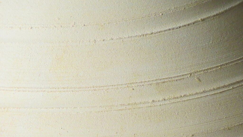 Close-up of light clay vessel with soft circular ridges, used as a calm textured background on the About Jo-Anne page.