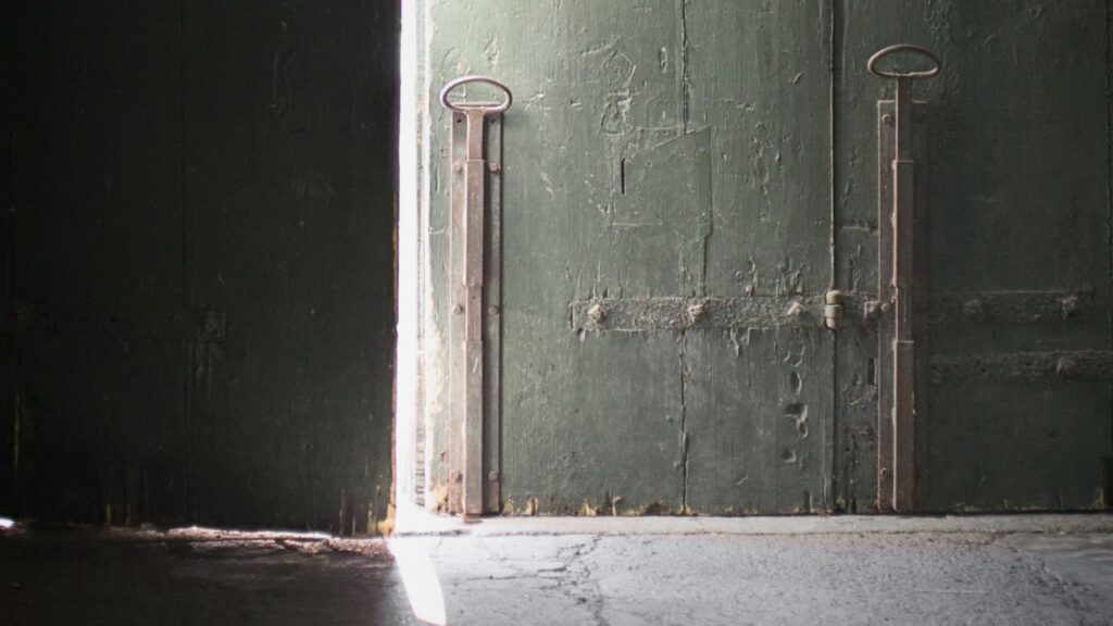 A thin seam of light through a half-open door — the moment before beginning.