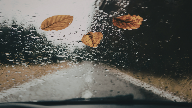 Rain on a mountain road seen through a car windshield, vertical format, symbolizing personal transition.