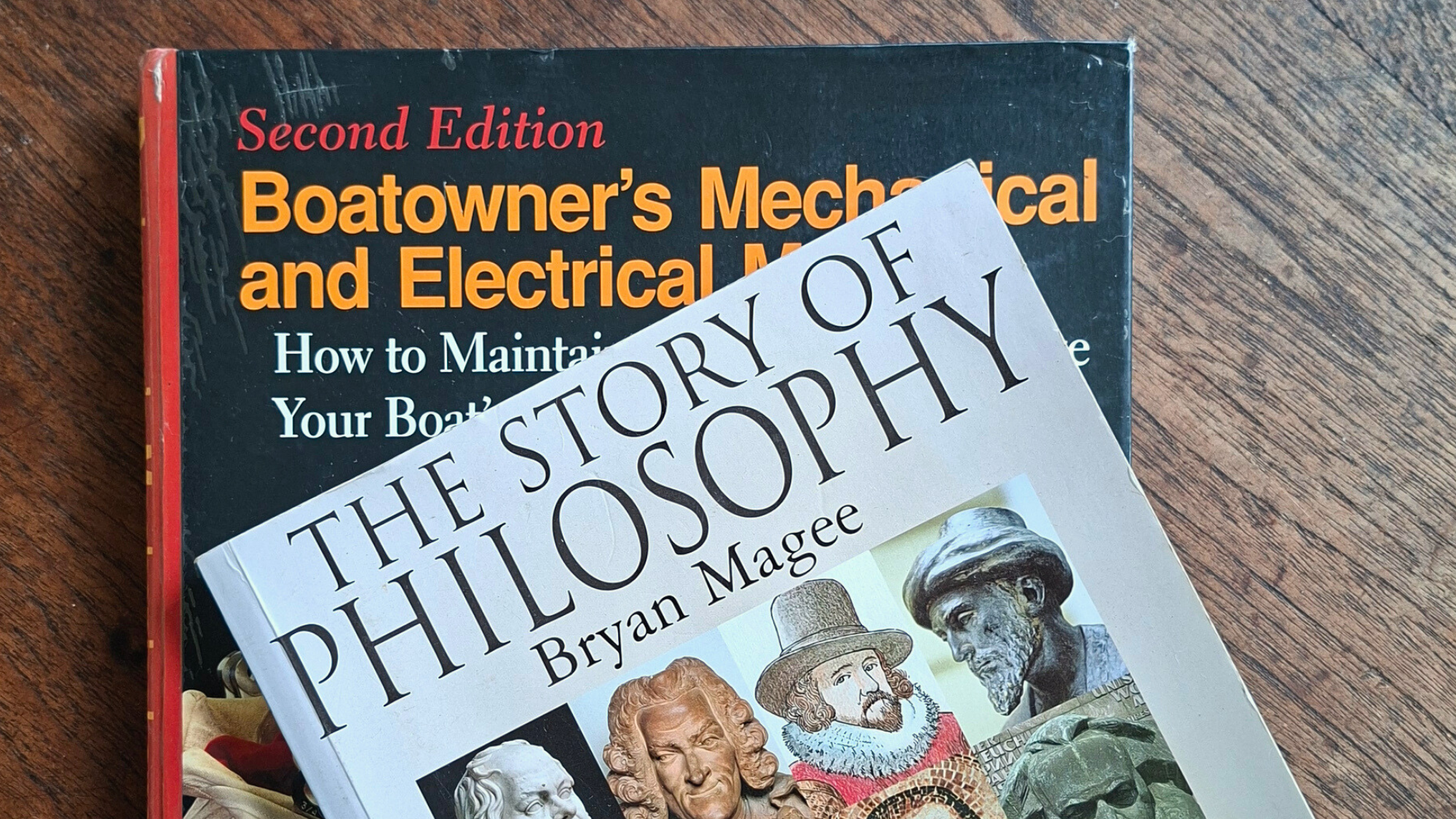 A tradesman's manual beside a philosophy text on a wooden table