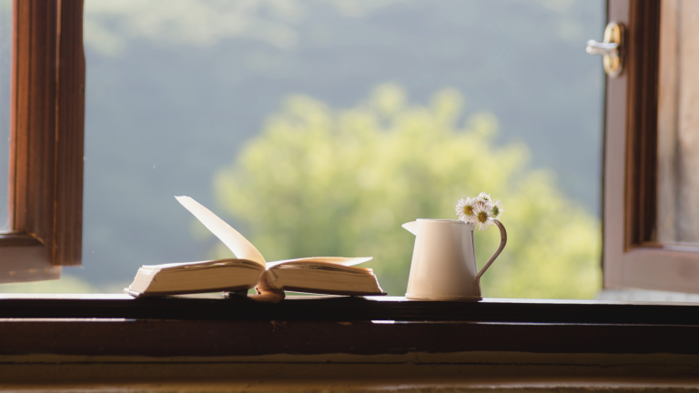 Open journal and ceramic mug on a wooden windowsill, framed by a window overlooking greenery — used for Notes Essay on choosing alignment over advancement.