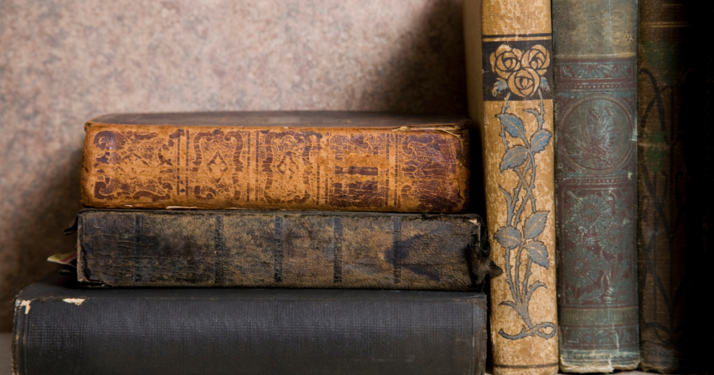 A small collection of worn journals and old books in warm, subdued light.