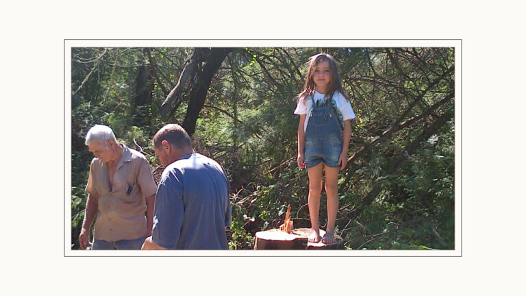 Angel barefoot on the stump of a newly felled blackwood tree. The woodcutter, Gus and Jessie nearby.